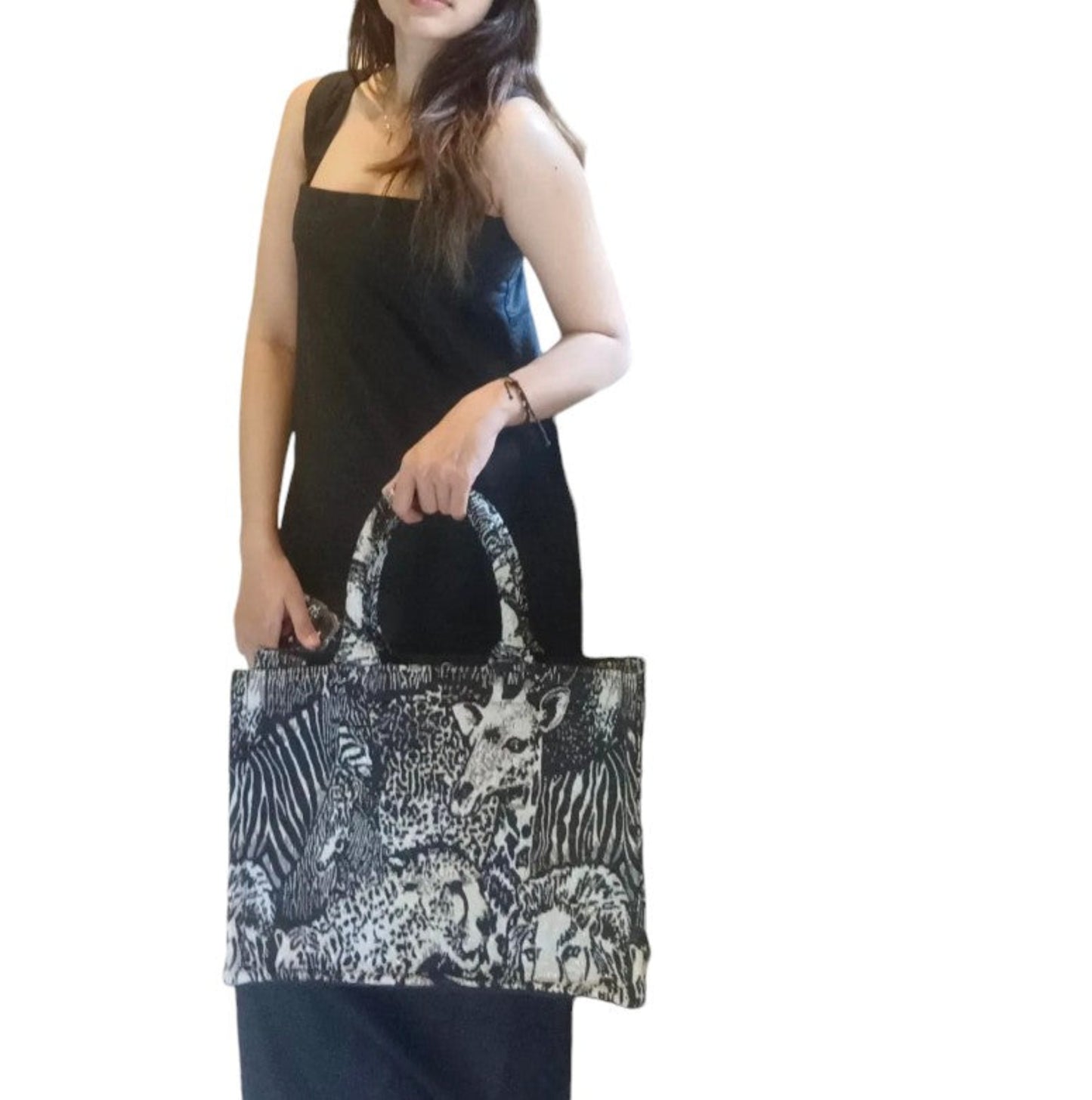 A model carrying a black and white book tote with wild animal prints in her hand.