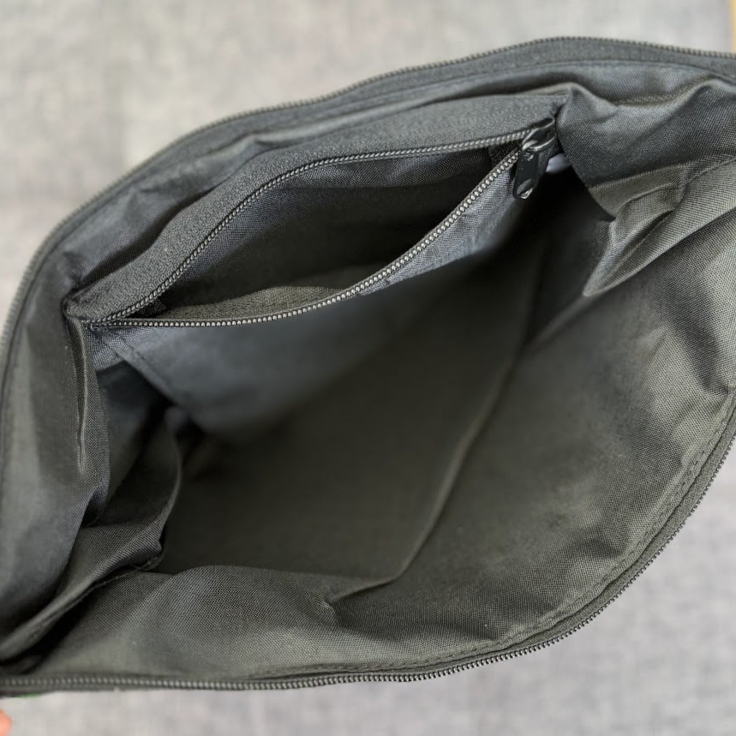 Inside a bag showing a basic black cotton fabric lining, a zip pocket, and a top zip closure.