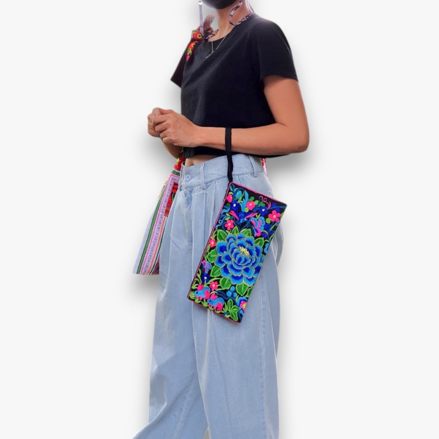 Model wearing a handmade Blue Camellia wristlet with vibrant floral embroidery, a stylish cotton bag for everyday fashion.