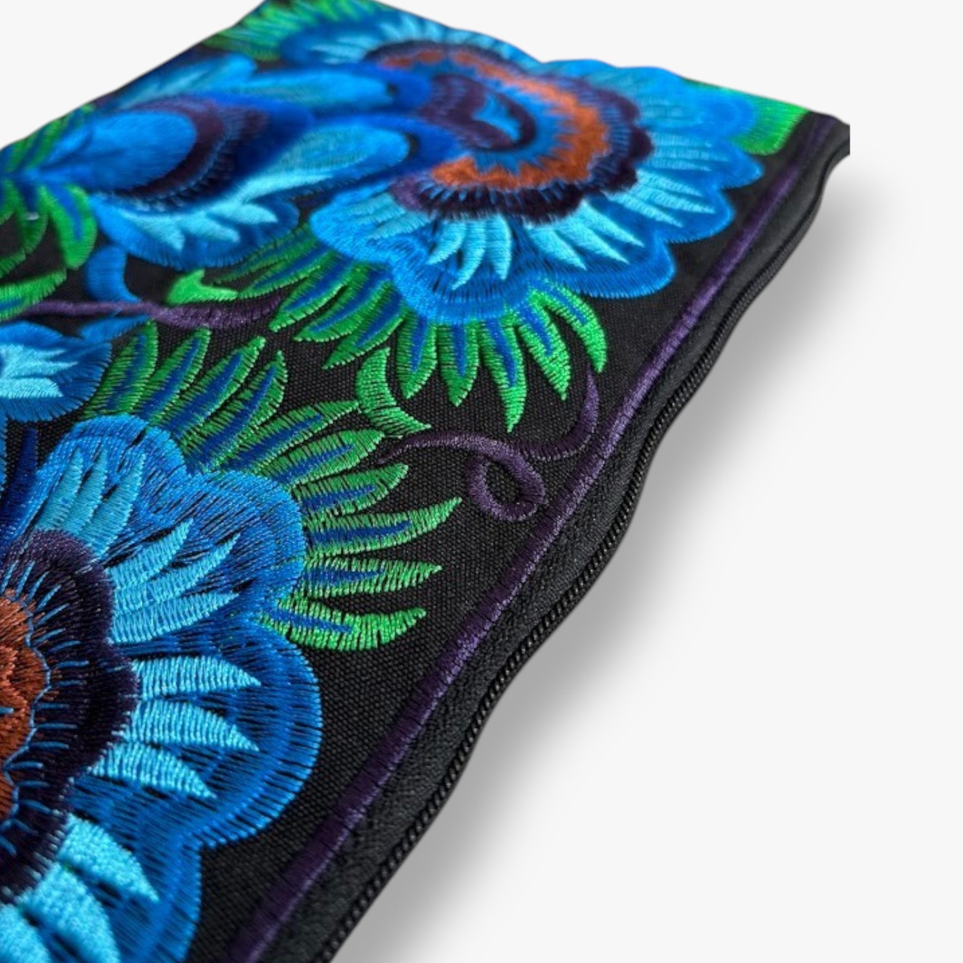Close-up of a detailed blue flower embroidered wristlet bag with green leaves on black fabric.