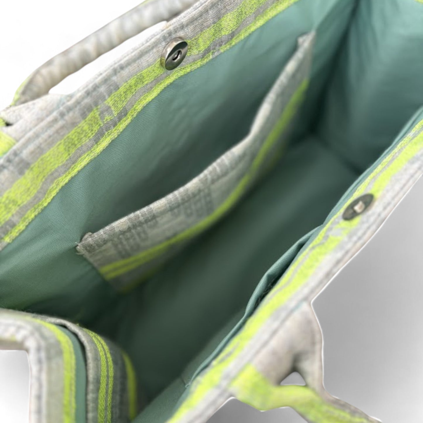 Interior of a neon green and light grey tote bag, displaying slip pockets, a magnetic clasp, and large capacity.