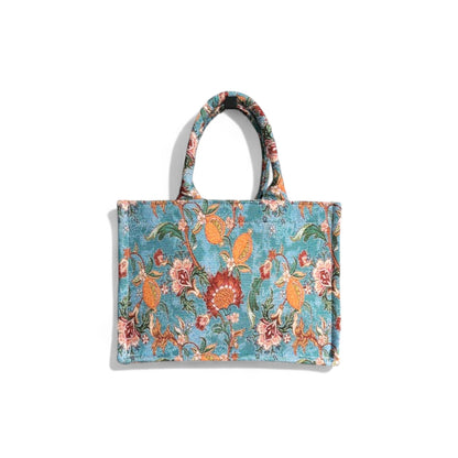 The textured surface of the blue vintage floral tote bag is shown in its front view details.