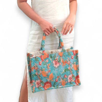 A person models the maxi-sized vintage blue floral tote bag, with the bag held at their front.