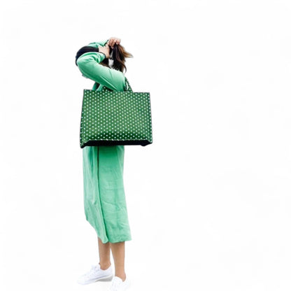 A model wearing a green tote bag with small white polka dots on her shoulder.
