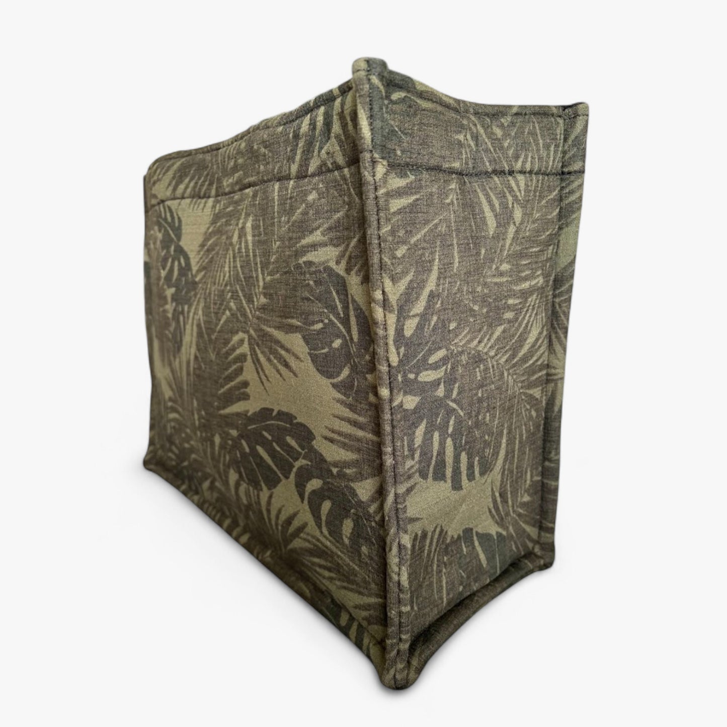 A green textured tote with monstera and palm leaf patterns viewed from the side.