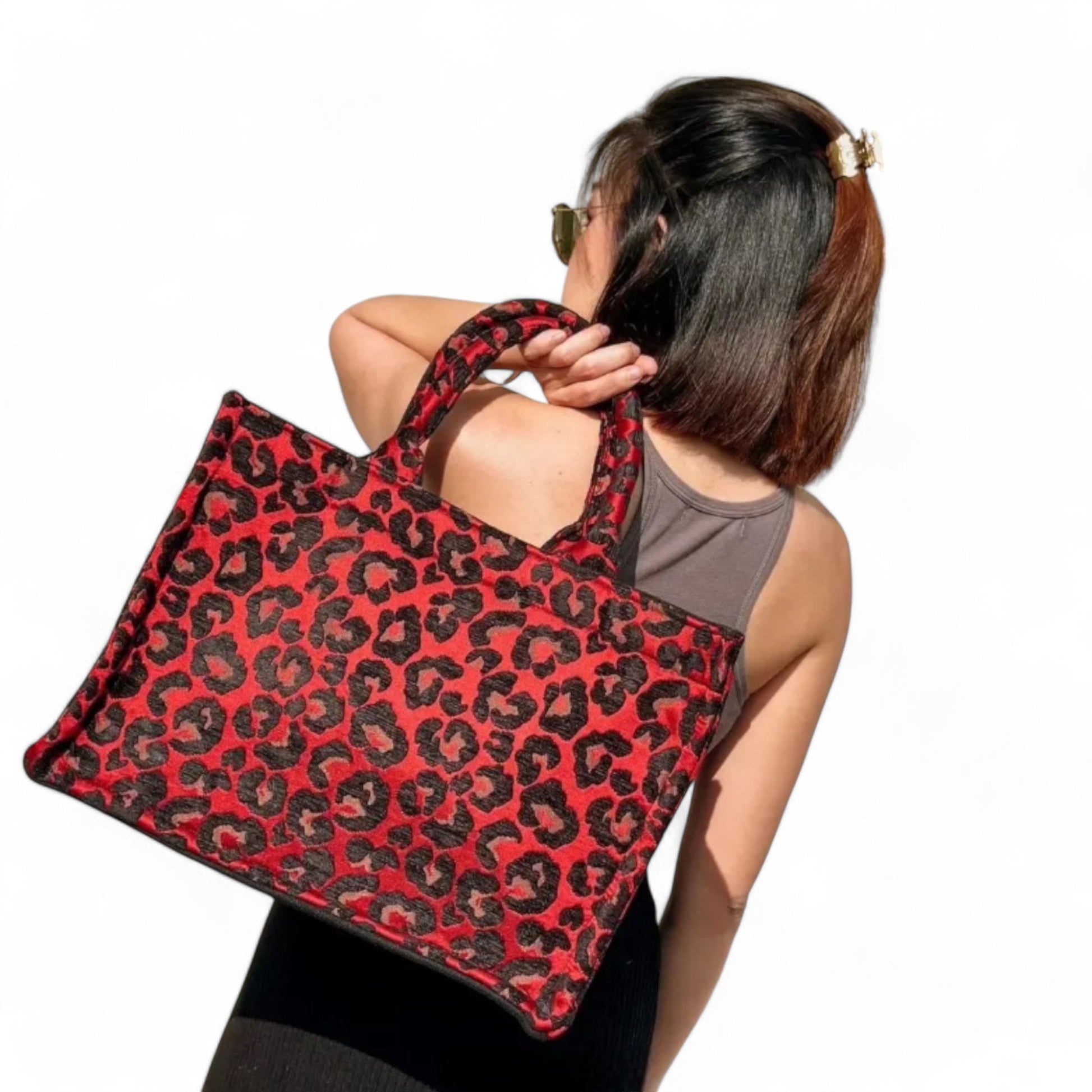 Back shot of a model holding a red leopard print tote bag.
