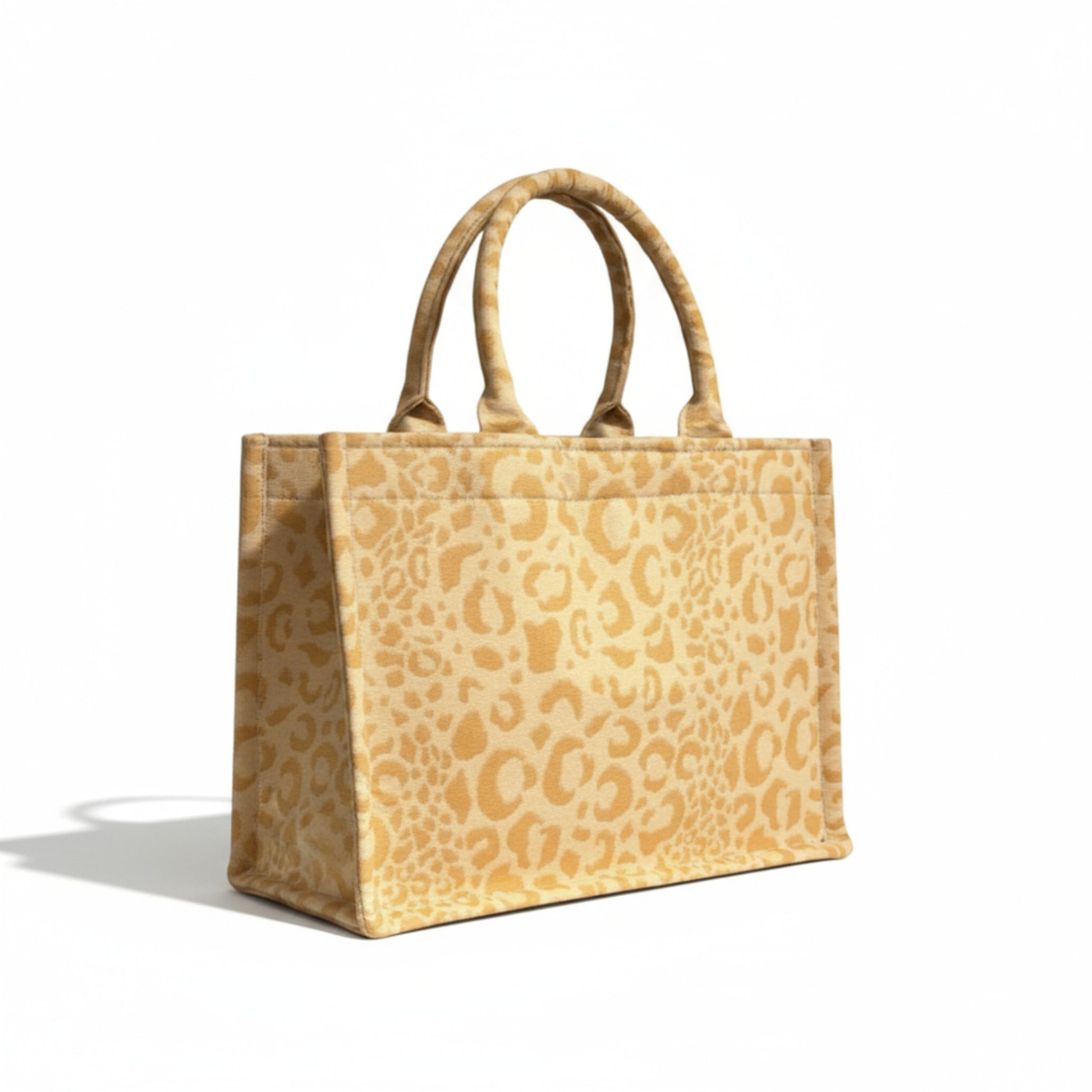 Angle view of a handmade yellow leopard tote with soft handles and a structured design.