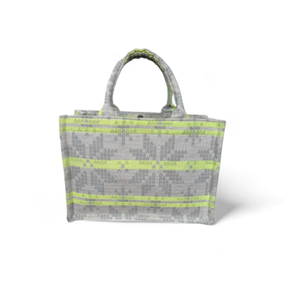 A tote bag with neon green stripes on light grey jacquard fabric.