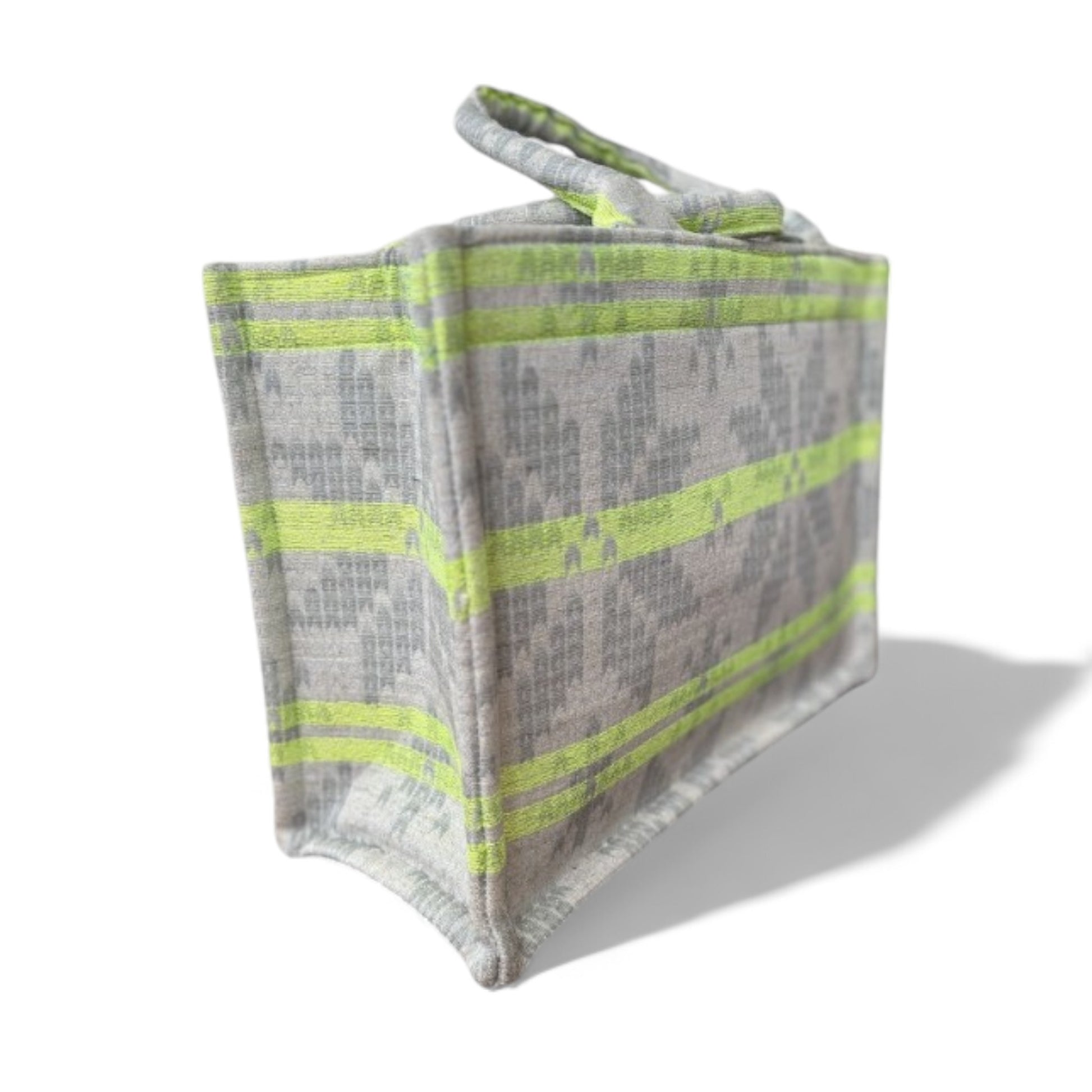 Close-up side view of a structured tote bag with neon green stripes on a light grey jacquard fabric.