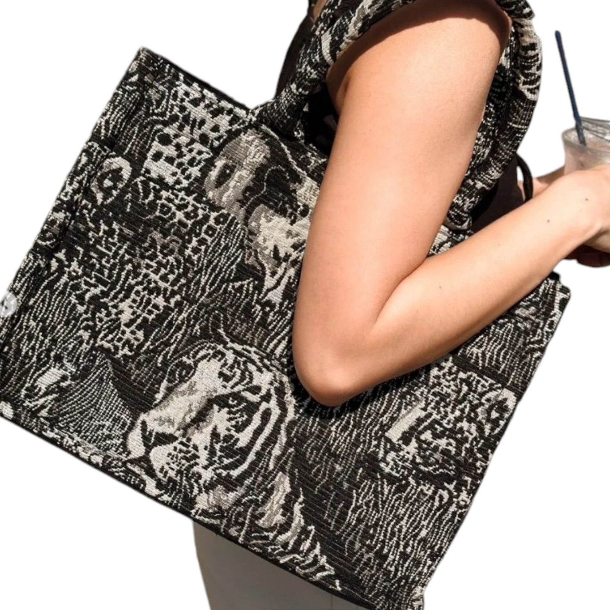 A model wearing a black and white tote bag with wild animal prints on her shoulder, showing its luxurious design.