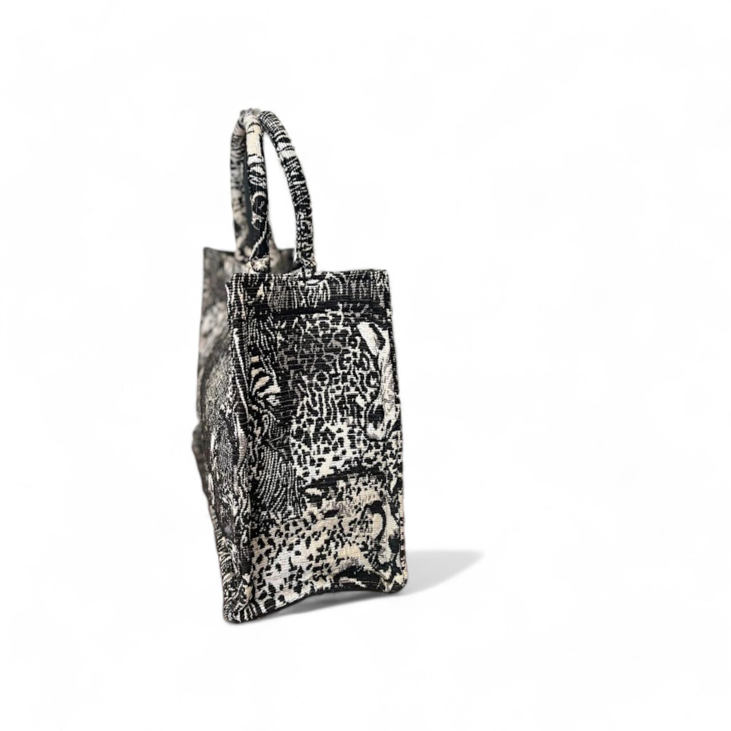Side view of a black and white book tote with wild animal prints.