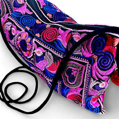 A close-up of a pink multi colour embroidered bag with intricate floral and bird patterns.