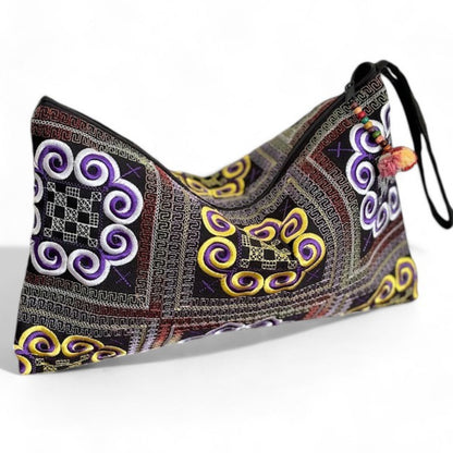 Handmade Hmong embroidered wristlet clutch with purple and yellow swirl motifs, and a mini pom-pom.