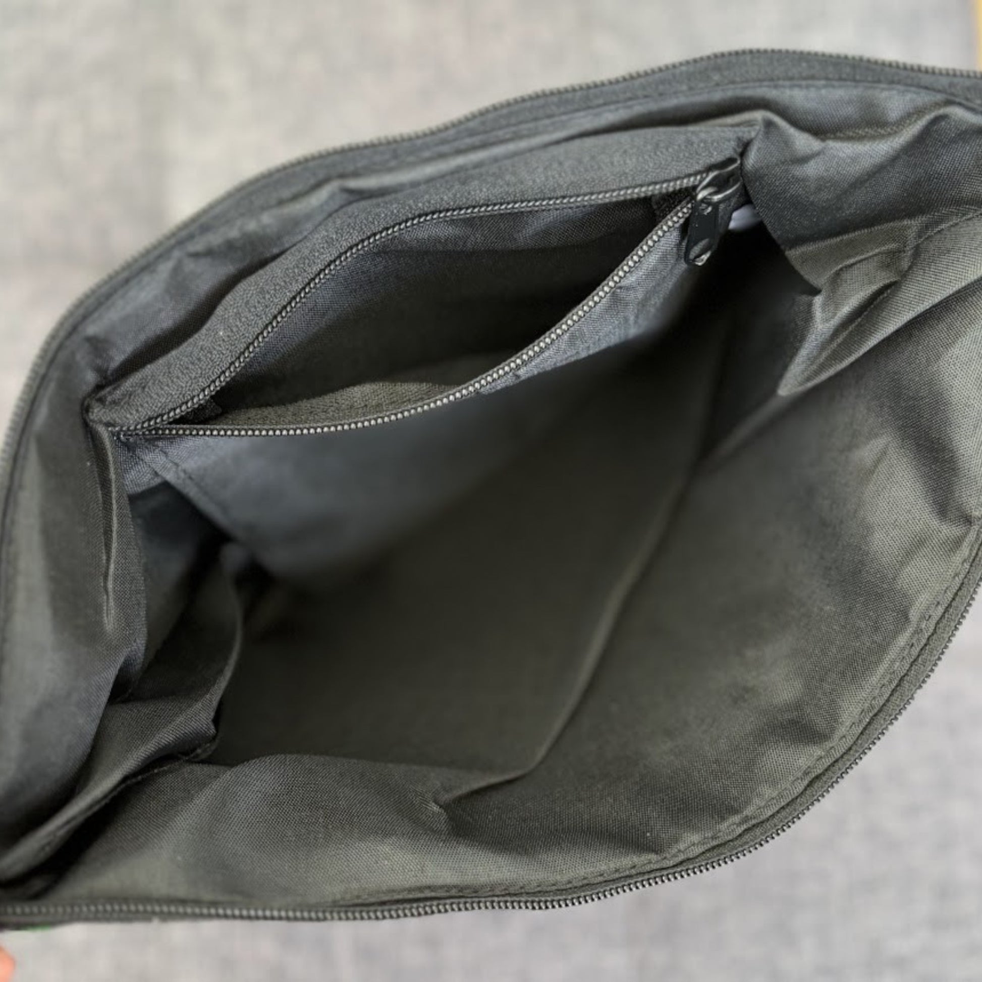 Inside a bag with a black lining, a zip pocket, and a top zip closure.