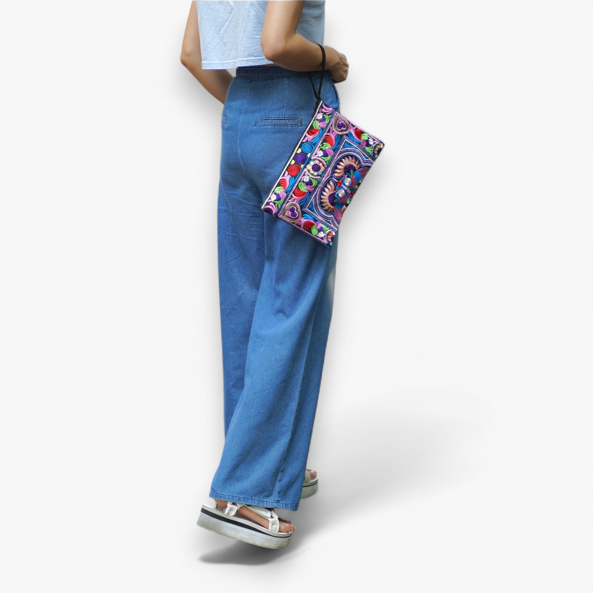 A model carrying a handcrafted embroidered wristlet bag with vibrant Hmong patterns on her arm.