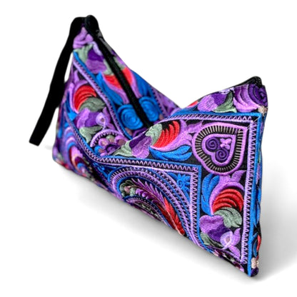 Angle close-up view of an embroidered pouch with a unique bird and floral patterns in purple, red, and blue.