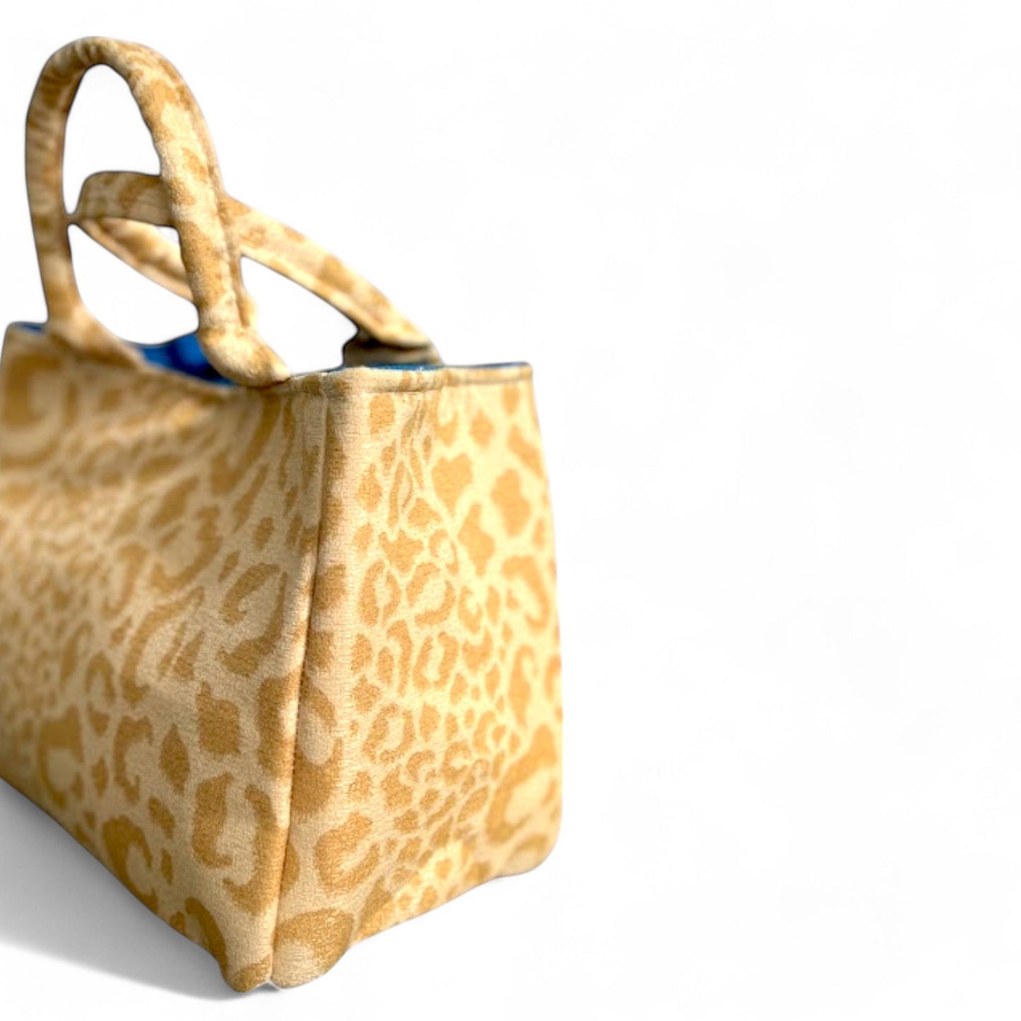 A side profile of a small handmade yellow leopard fabric tote. 