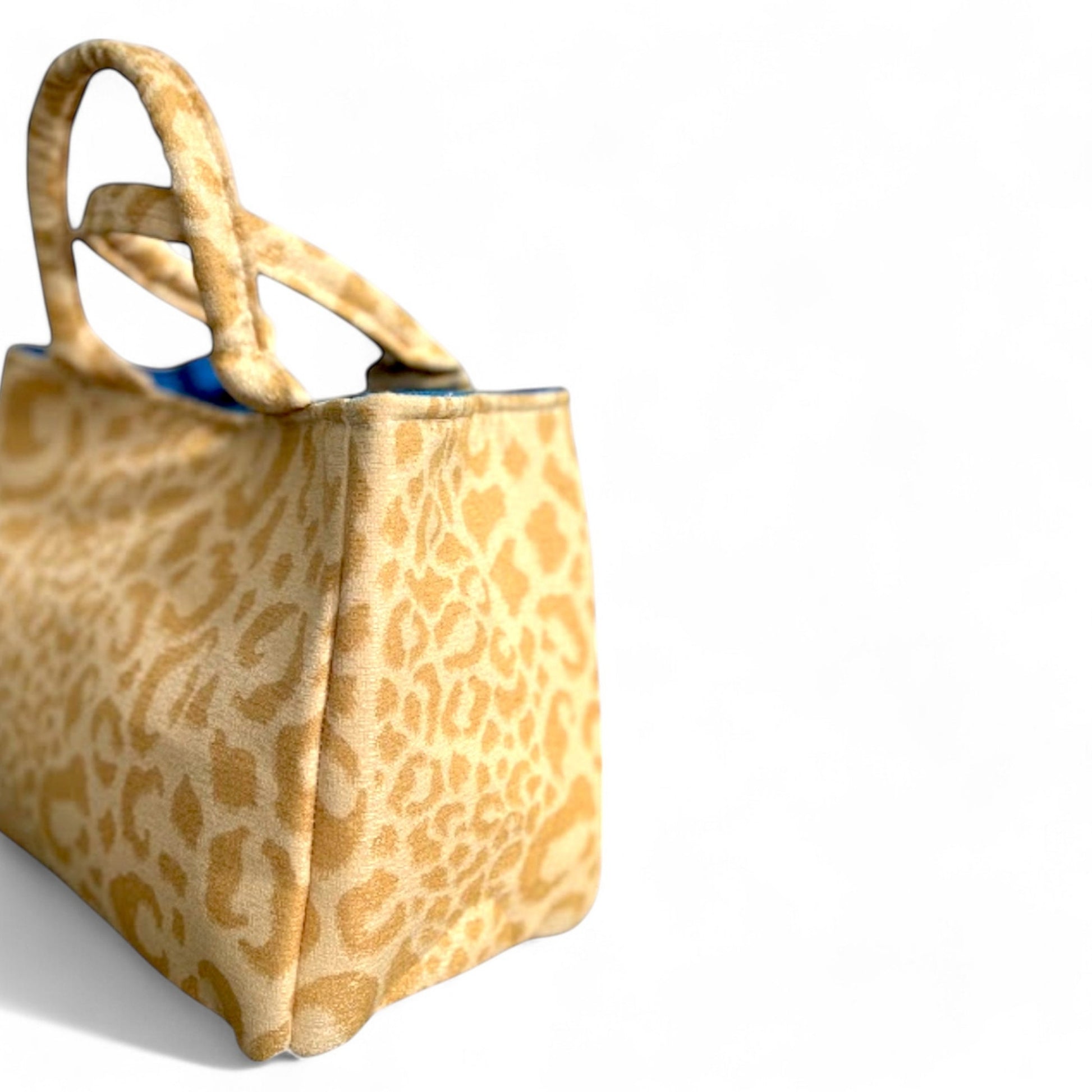 A side profile of a small handmade yellow leopard fabric tote. 