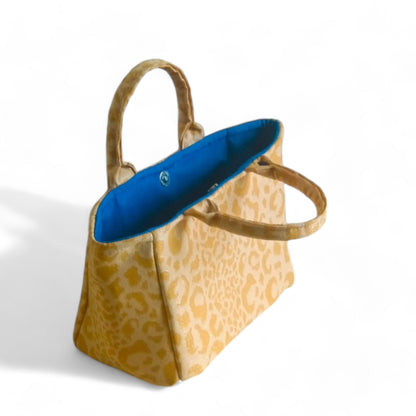 Top view of a handmade yellow leopard fabric tote bag with blue lining.