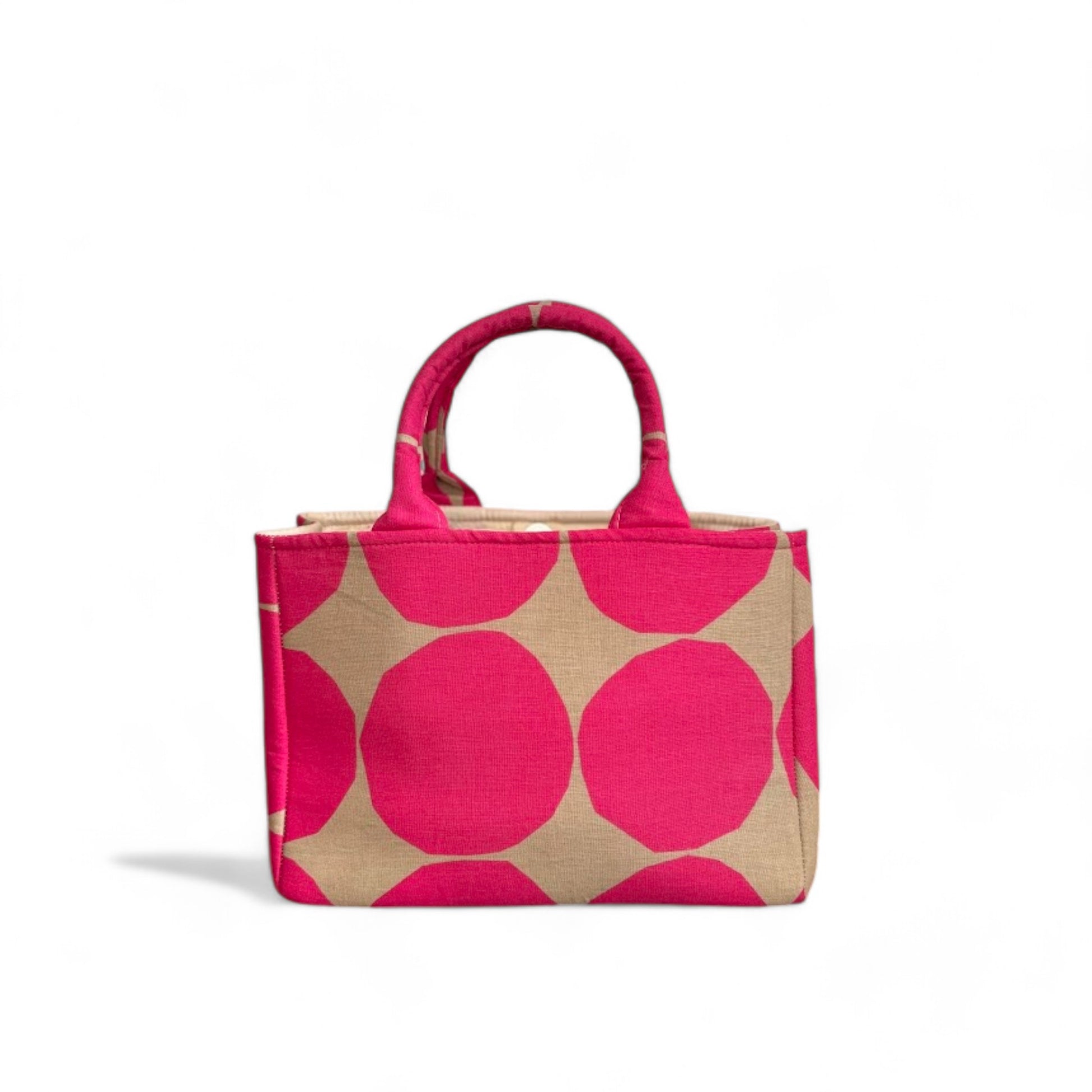 A front view of a handmade fabric mini tote with hot pink polka dots on a tan background.