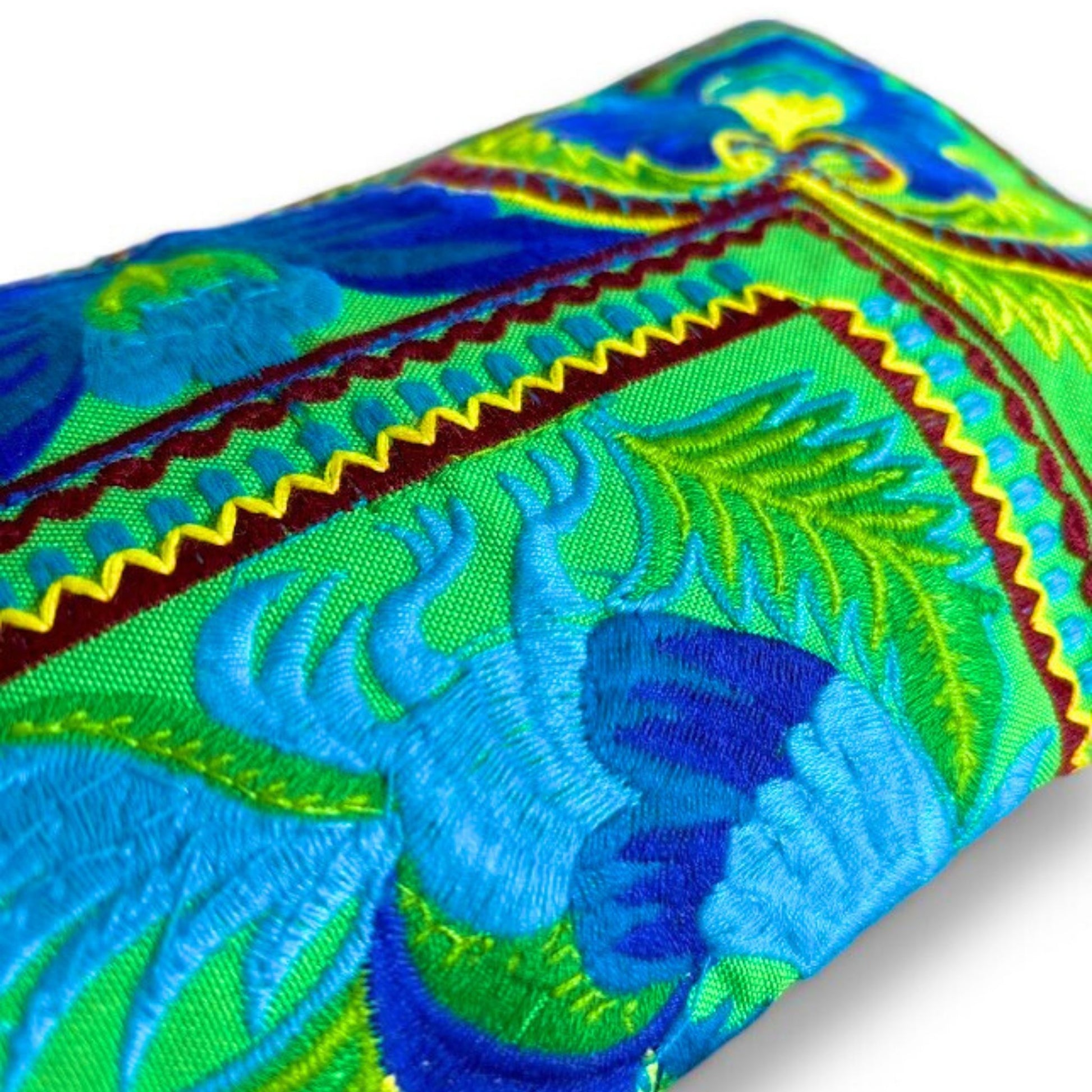 Close-up of a wristlet clutch showing intricate Hmong embroidery with vibrant blue and green.