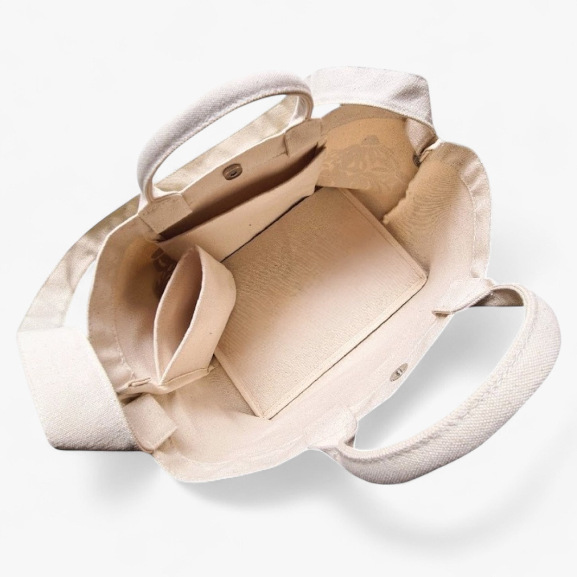 Interior of a canvas tote with a shoulder strap, top handles, a pocket, bottle holder, and strong base.