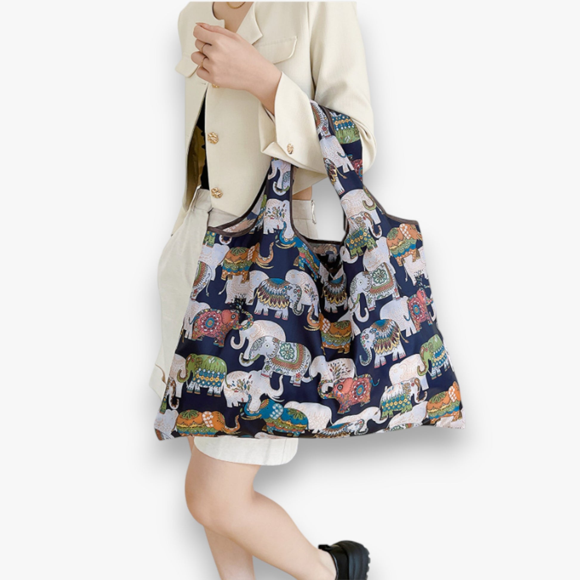 Person holding a navy nylon tote bag with a colourful elephant pattern.