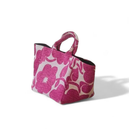 The bag with top handles stands upright, showcasing its durable base and bold magenta floral design.