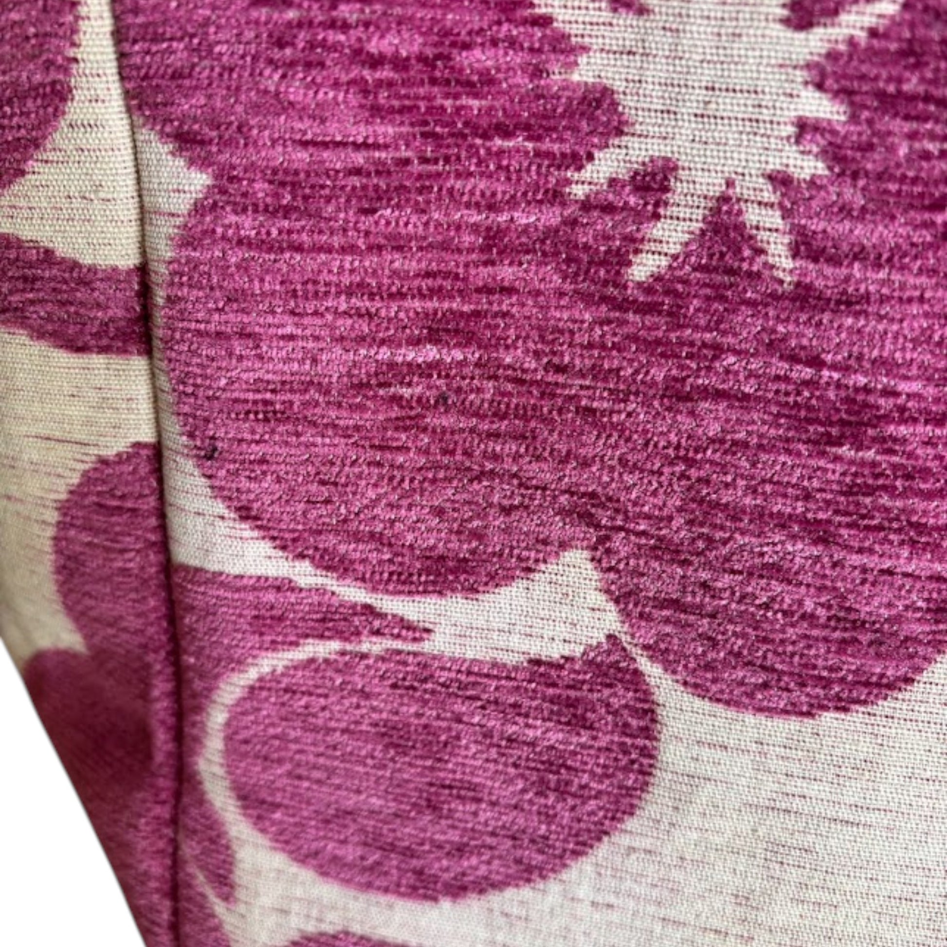 Close-up of a textured beige fabric with big and bold magenta floral patterns.