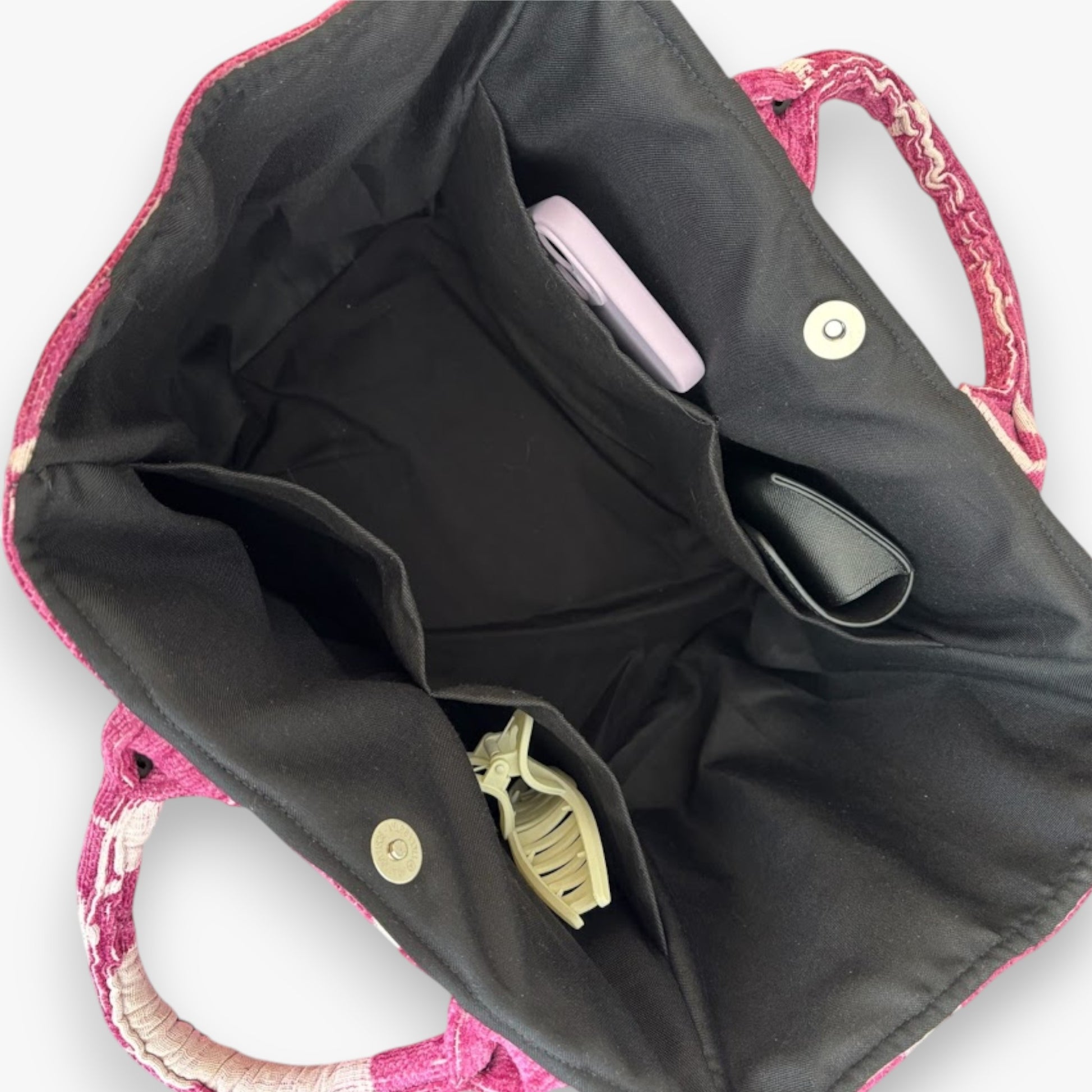 An open magenta floral tote bag showing black linging, roomy interior, pockets, and magnetic closure.