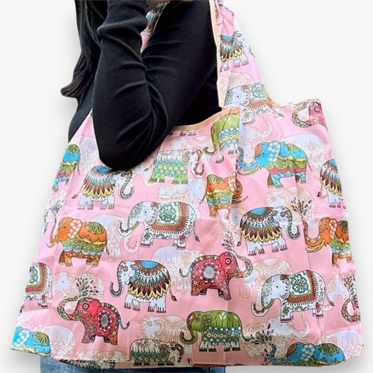 Close-up of a person carrying a pink nylon tote bag with colourful elephant patterns on the shoulder.