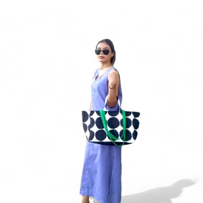 A woman carrying a tote bag with black and white polka dots in the crook of her arm.