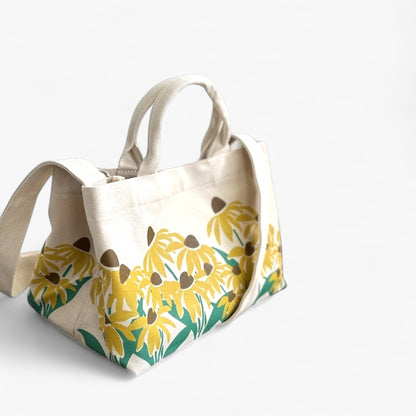 Side view of a canvas tote bag with sunflower print, sturdy handles, and crossbody strap.