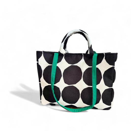 Shopper tote bag with black polka dot pattern, top handles, and green straps.