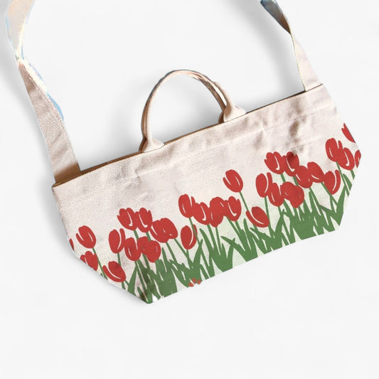 A durable canvas tote bag with red tulip prints, top handles, and a shoulder strap.